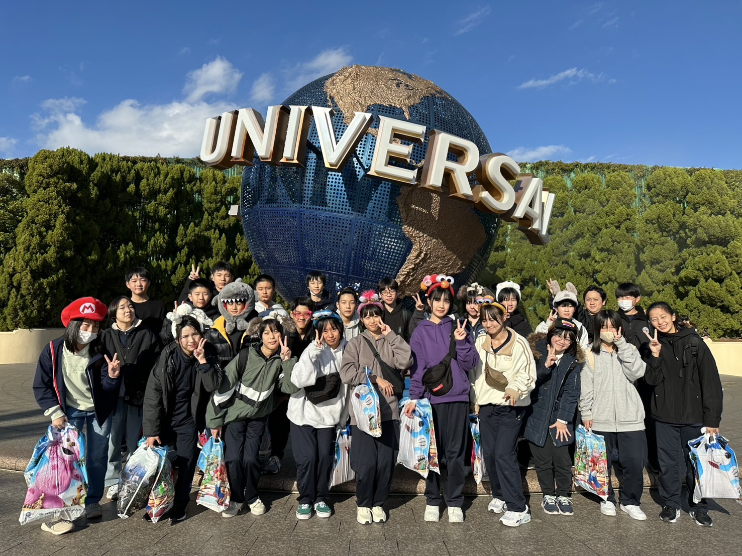 ユニバーサル・スタジオ・ジャパンの地球儀の前で生徒たちが記念撮影をしている写真