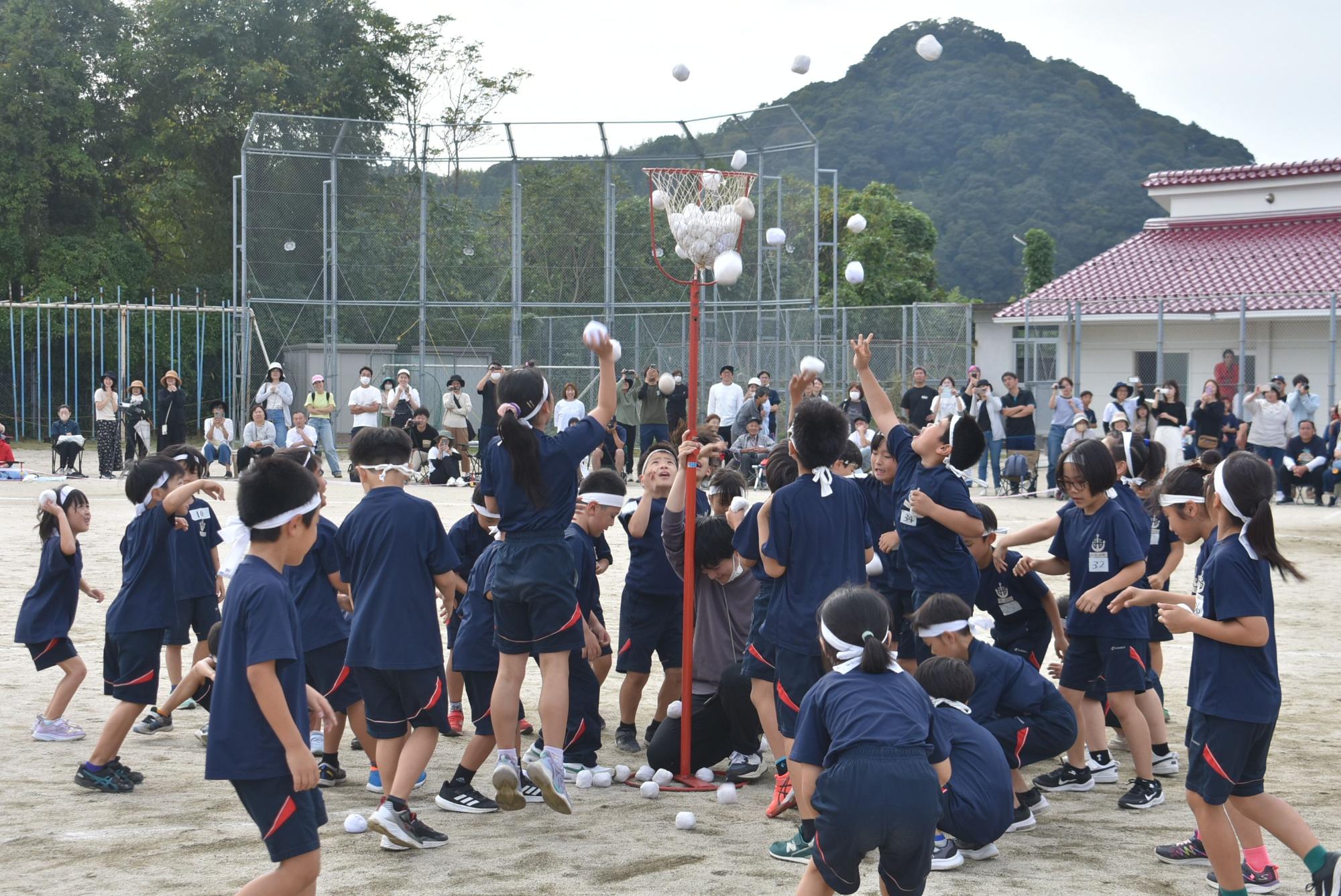 校庭で児童たちが玉入れをしている写真