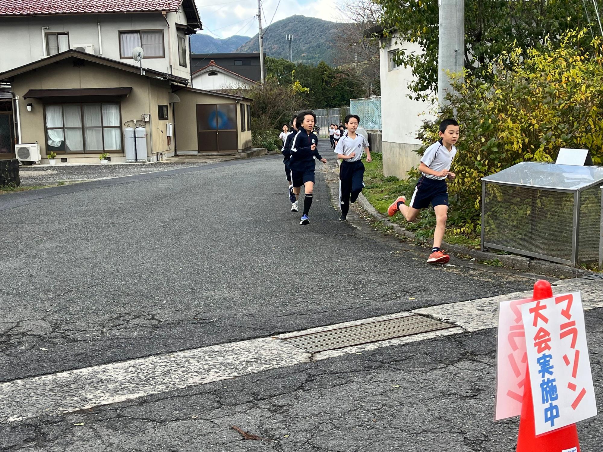 校外でマラソン大会に出場し走る児童たちの写真