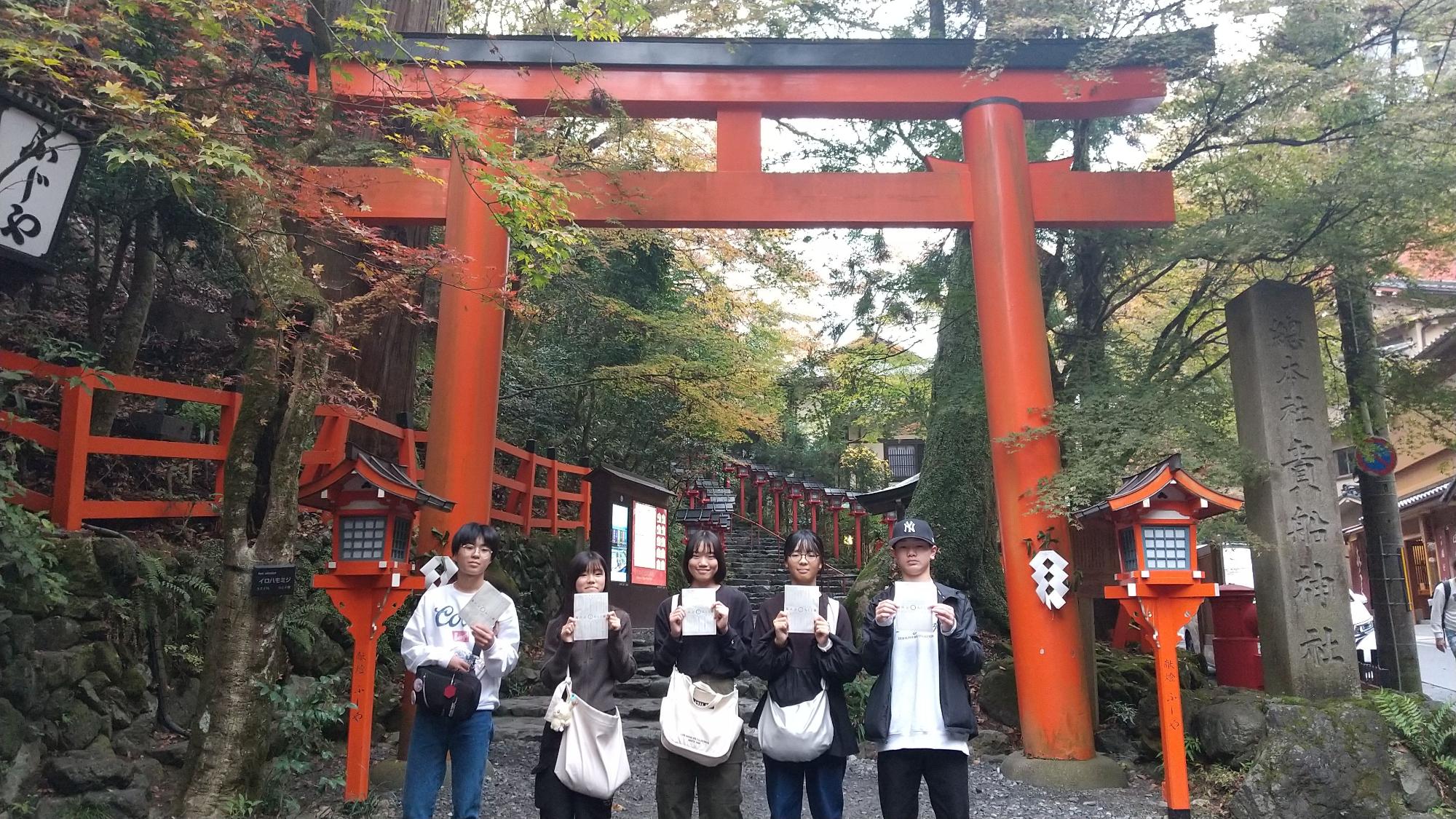 神社の鳥居の前で生徒たちが記念撮影をしている写真