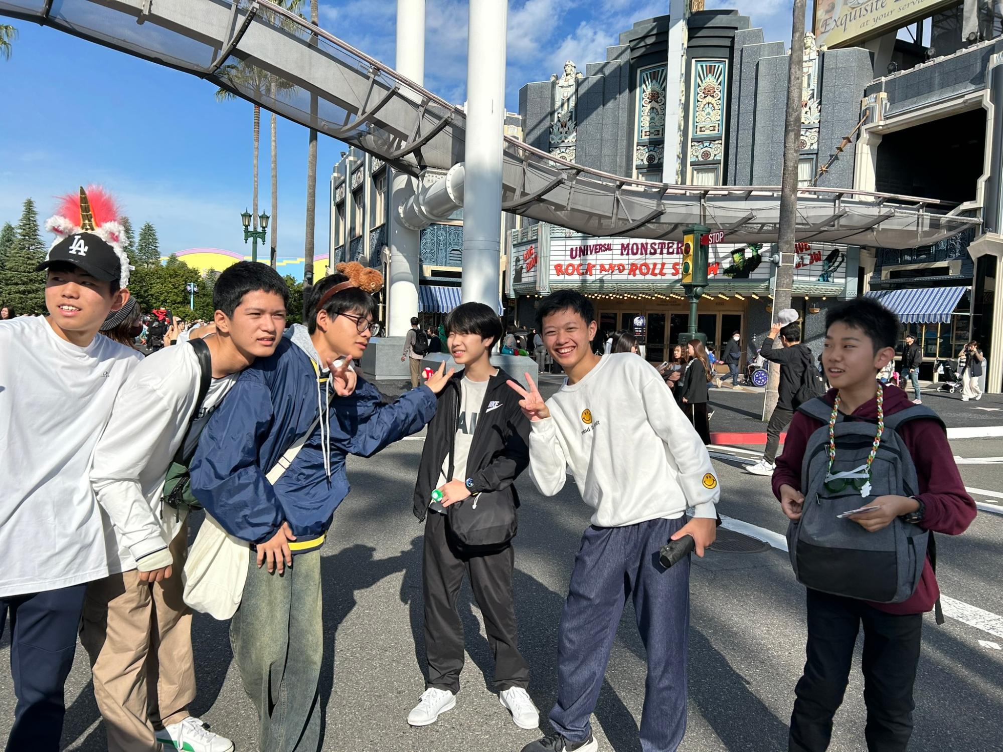 テーマパークの入口付近で生徒たちが笑顔でポーズをとっている写真