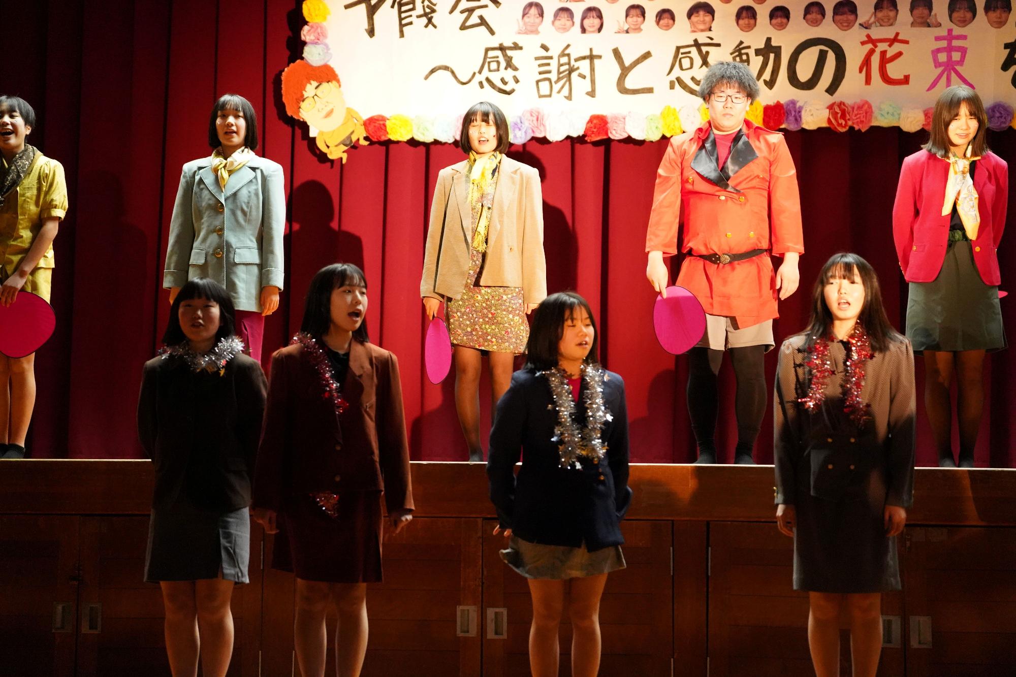 舞台上で衣装を着た生徒たちが合唱をしている写真