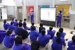 座っている生徒たちの前で代表の生徒たちがスクリーンを使って発表している写真