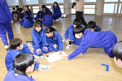 フロアでグループに分かれ、生徒たちが相談しながら活動している写真