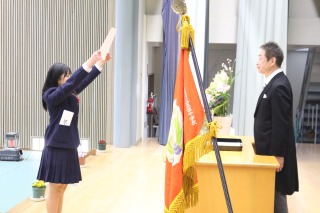 式典で女子生徒が壇上で証書を受け取っている写真