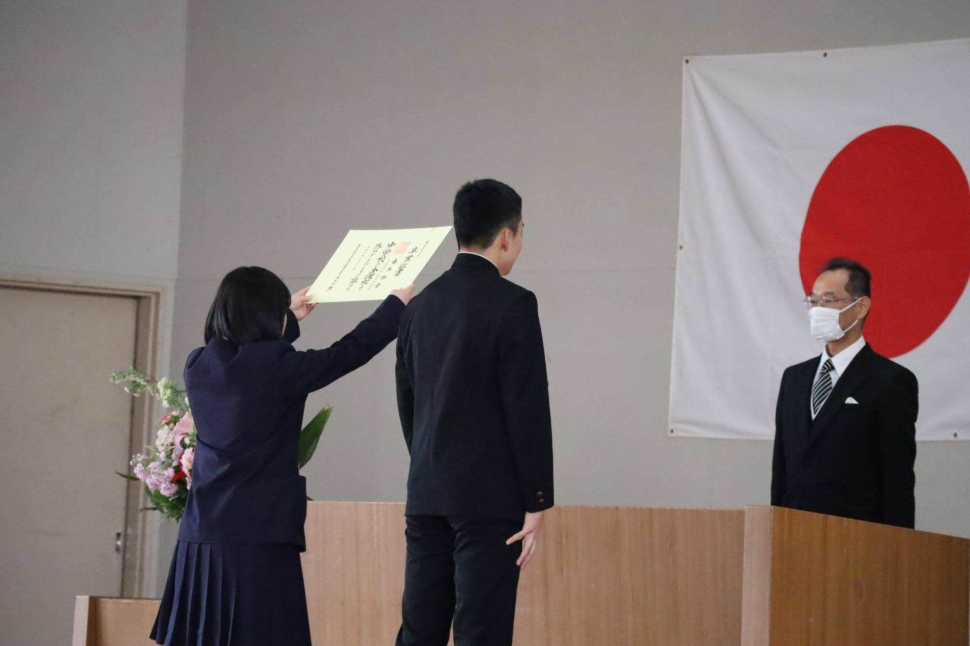 壇上で生徒が賞状を受け取っている写真