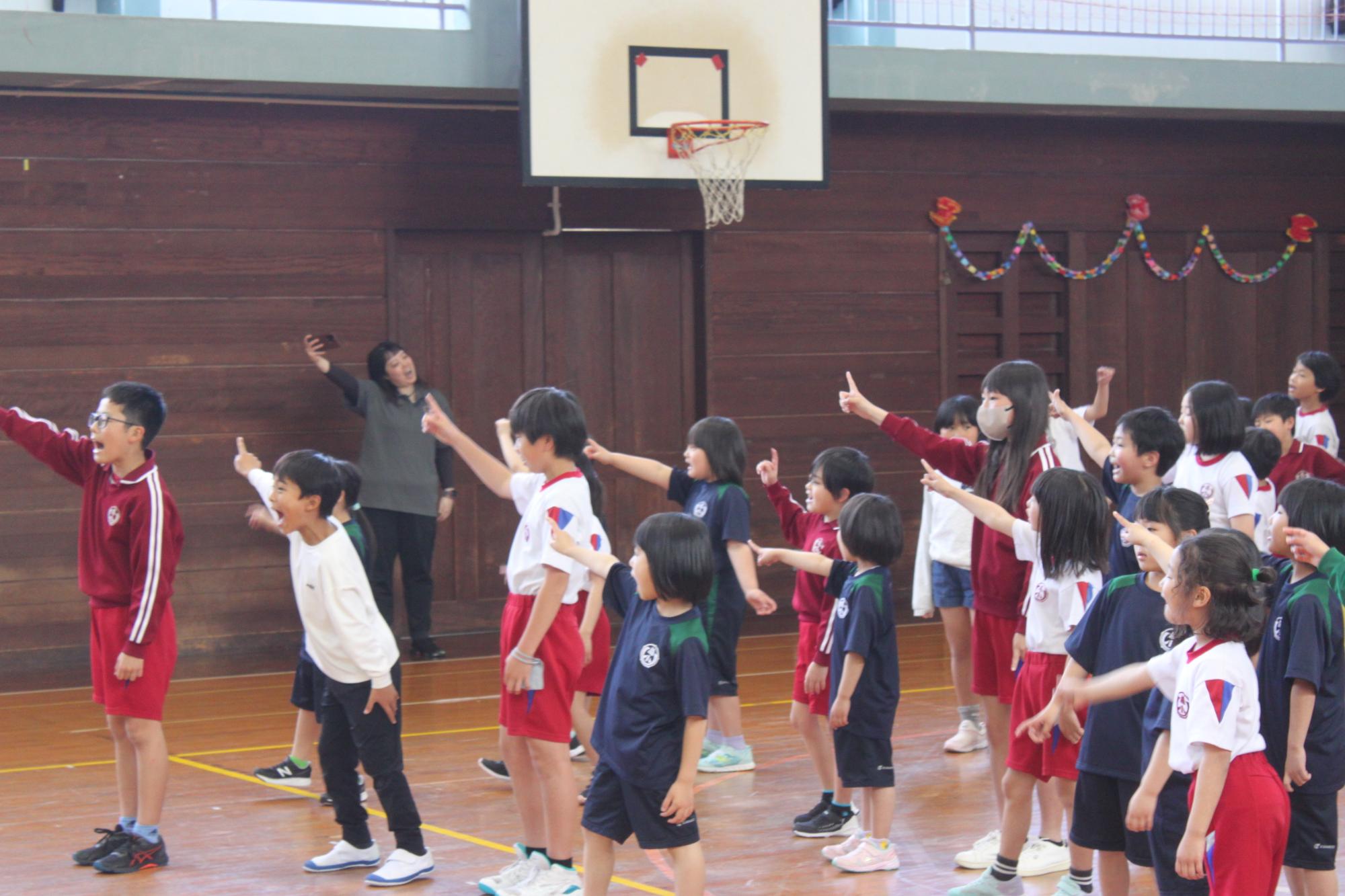 体育館でたくさんの児童たちが体を動かしてダンスをしている写真