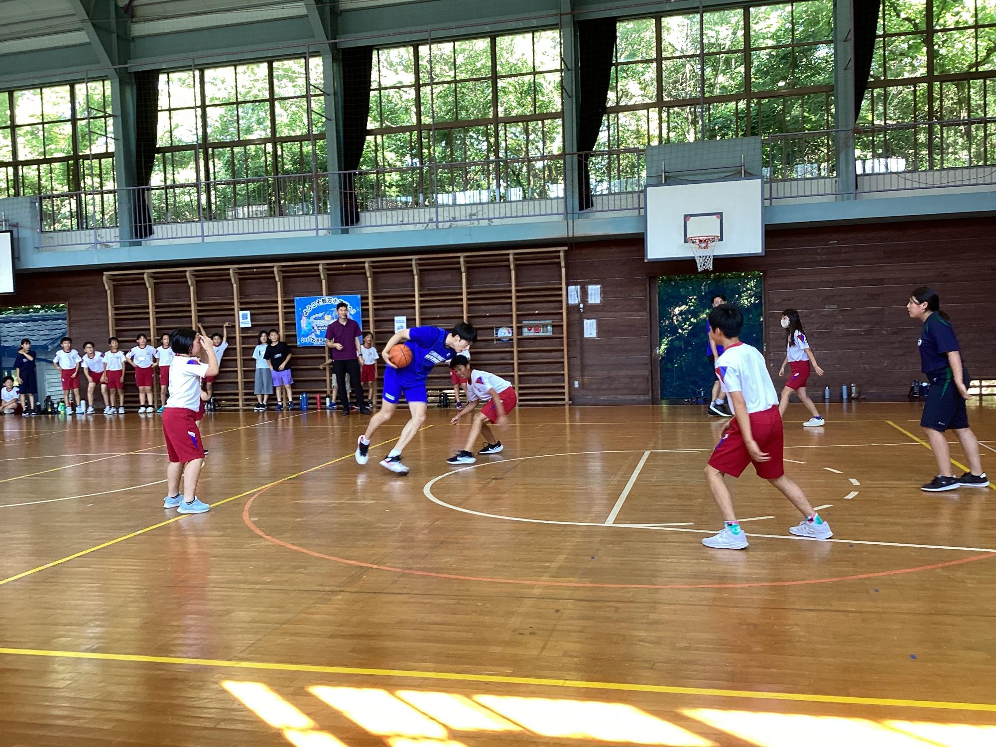 体育館で生徒たちがバスケットボールの試合をしている写真