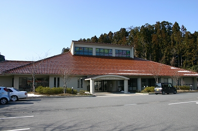 赤い屋根と大きな採光窓が特徴的で、手前に駐車場がある隠岐の島町立図書館の写真