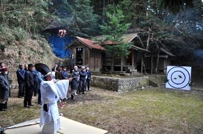 カラスと鼠の絵の描かれた的に向けて弓を引いている様子の山田客祭風流の写真