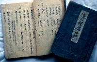 表紙の見える一冊と、開かれている一冊が並んでいる、佐々木家庄屋文書の写真