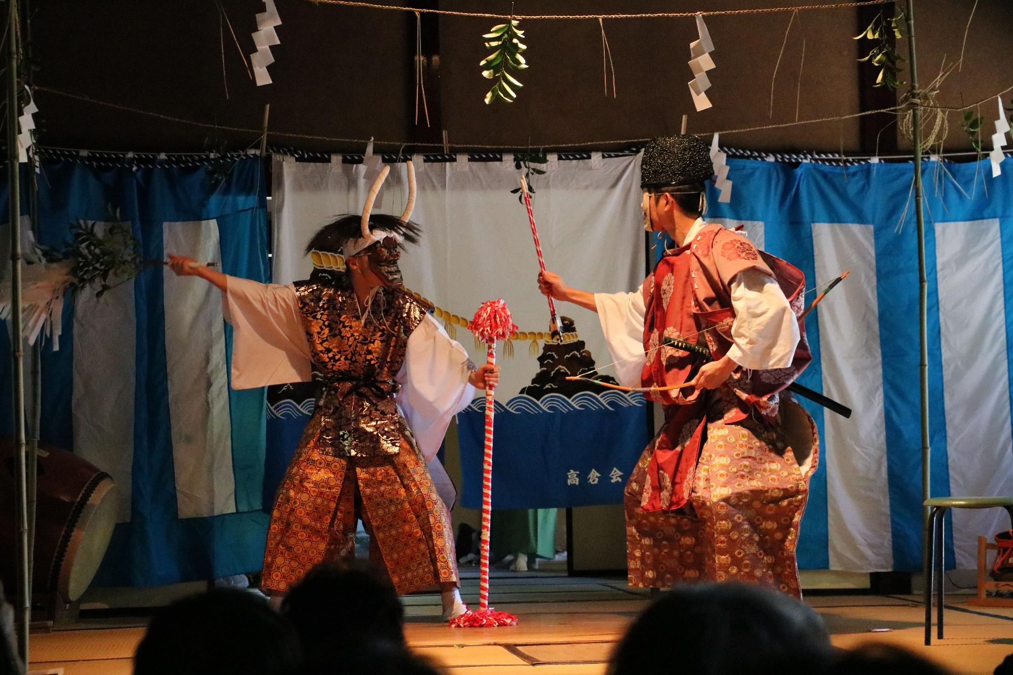 神楽公演の写真。2人の男性が向かい合って神楽を舞っている。