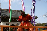 面と煌びやかな赤い服装で行われている隠岐国分寺蓮華会舞の写真