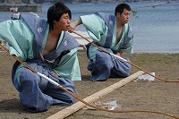 紺色と水色の服装で弓を持ってかがんでいる様子の花生神社祭礼風流の写真