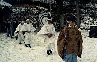 雪が積もっている中、射的の的が置いてあり3種類の服装の人々が歩いている山田客祭風流の写真