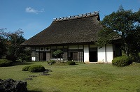 かやぶき屋根と白い壁の都万目の民家の写真