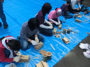 ナイフで竹を削っている親子たちの写真