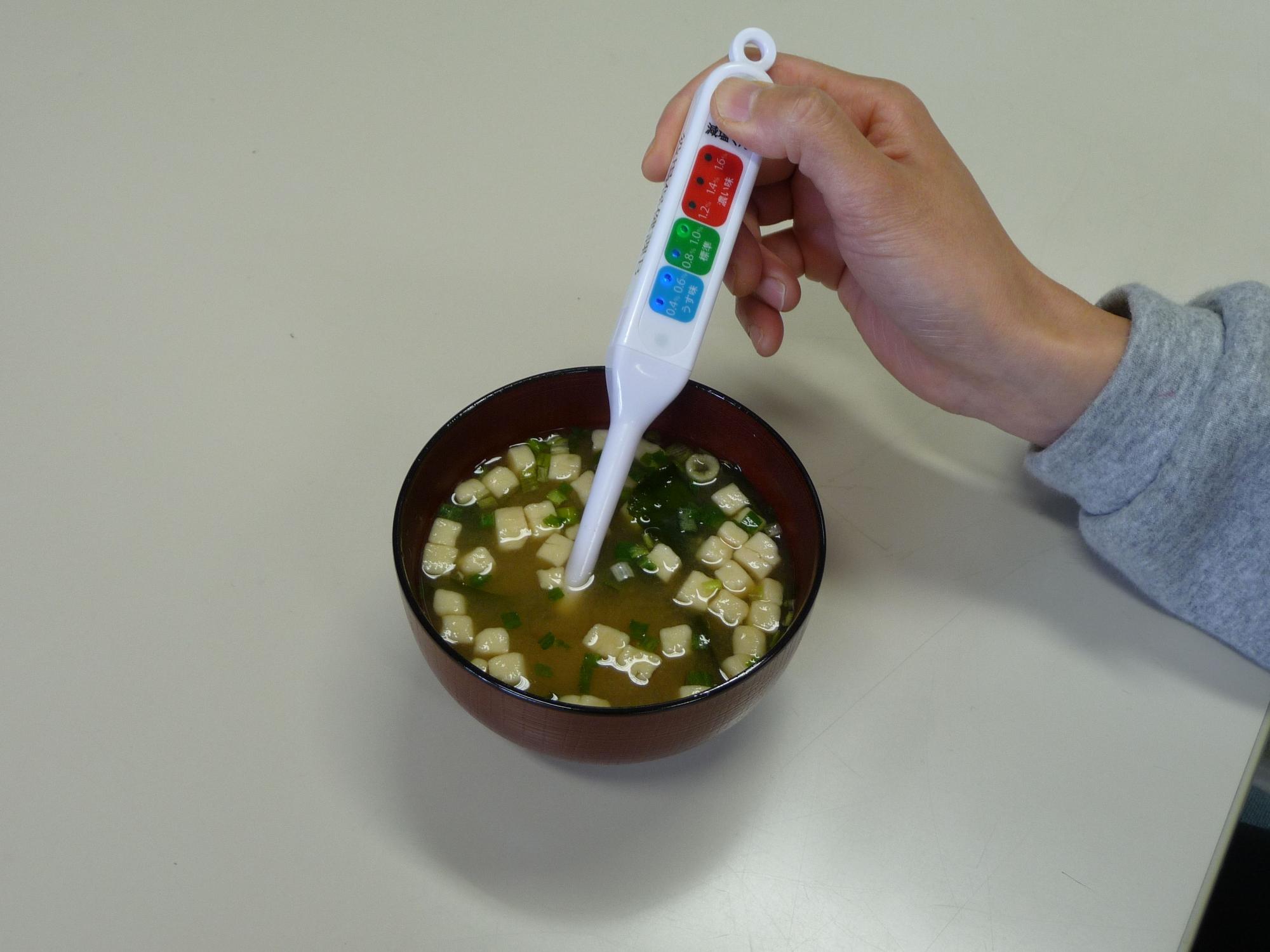 味噌汁の塩分濃度を測定器を使って計っている写真
