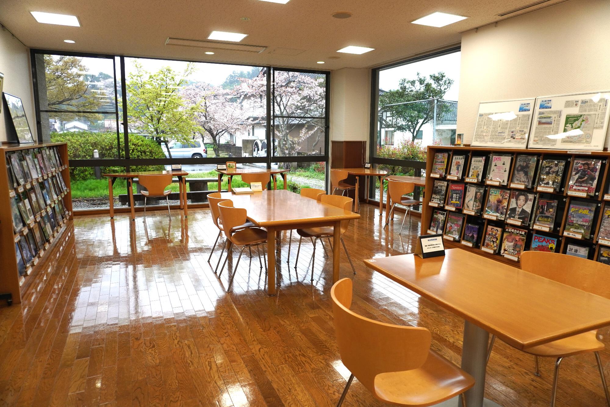 数台のテーブルと椅子が置かれた雑誌コーナーの写真