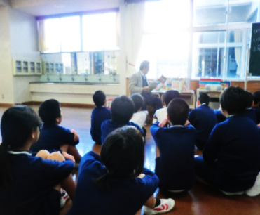 先生の読み聞かせを真剣に聴いている児童たちの写真