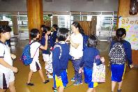 荷物を持った児童たちが会場のホールにいる写真