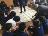 児童たちが床のいぐり凧を囲んでいる写真