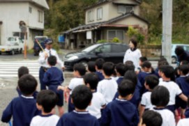 自動車の前で説明している講師の話を聞いている児童たちの写真