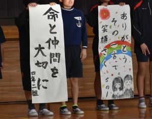 複数の児童が大きな紙に書かれた人権標語を掲げている写真