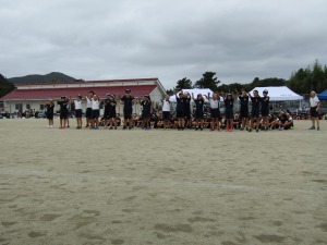 運動場で多くの児童たちが一列に並んでポーズをとっている写真