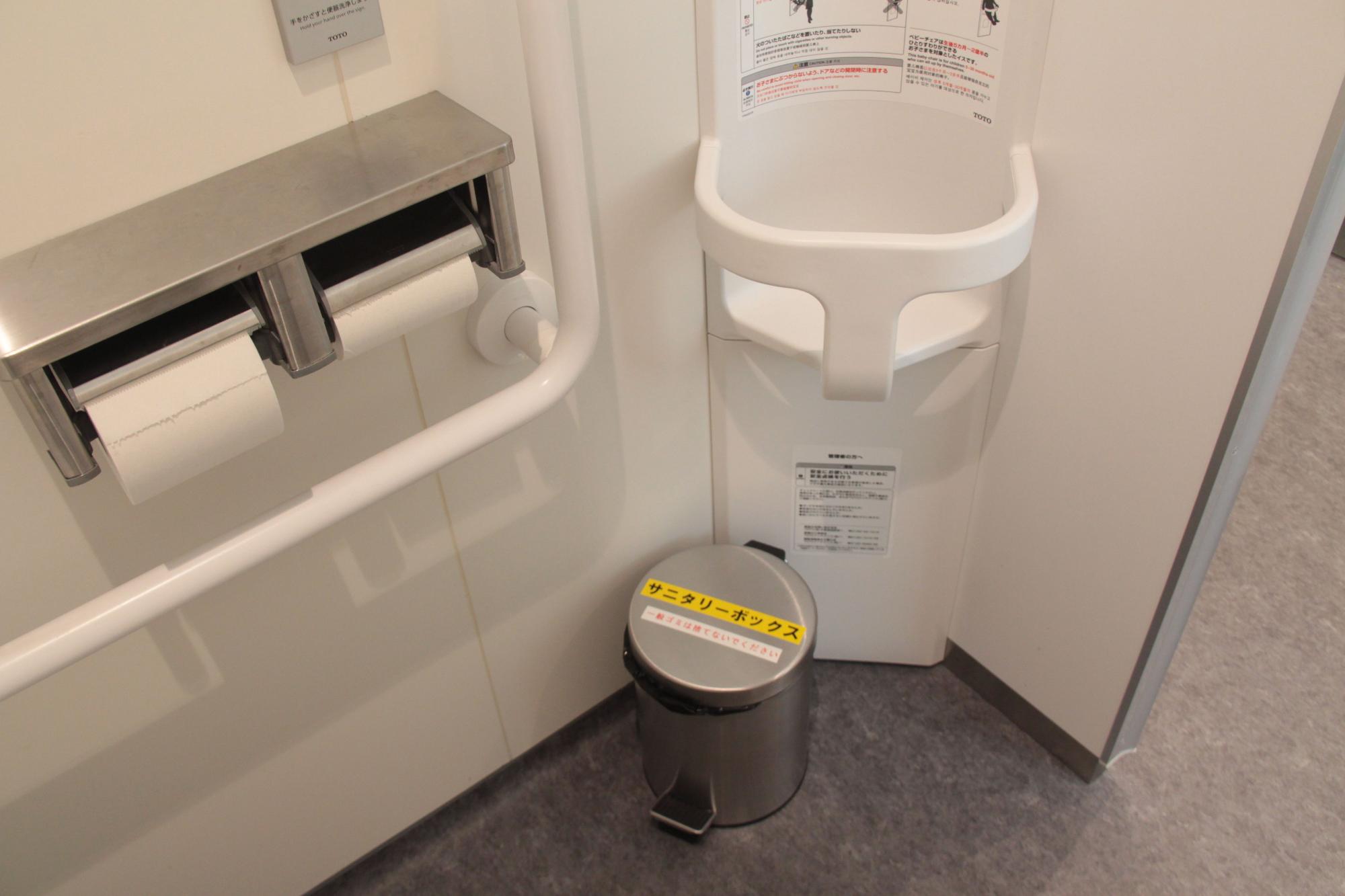 個室トイレ内の片隅に置かれた、円柱型で金属製のサニタリーボックスの写真