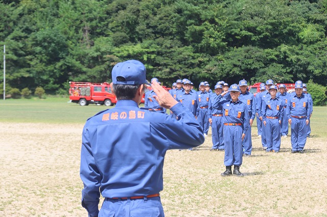 消防団員の男性が向かい合って敬礼し合っている写真