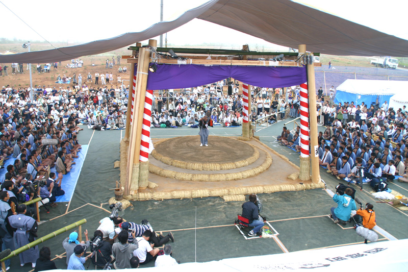 屋外に設置された土俵の周りにたくさんの人が座っている写真