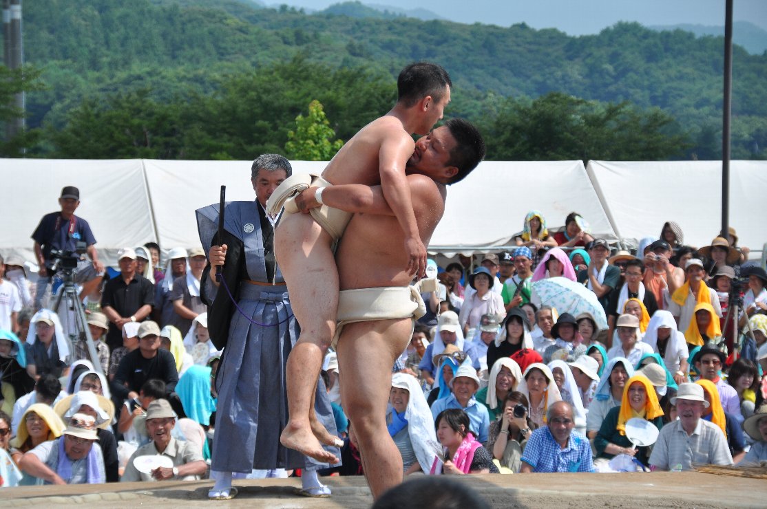 相手力士の回しを掴んで持ち上げている力士の写真