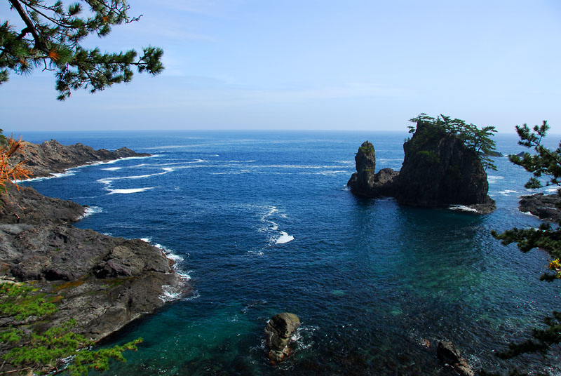 青く澄んだ海に岩場が突き出ている写真