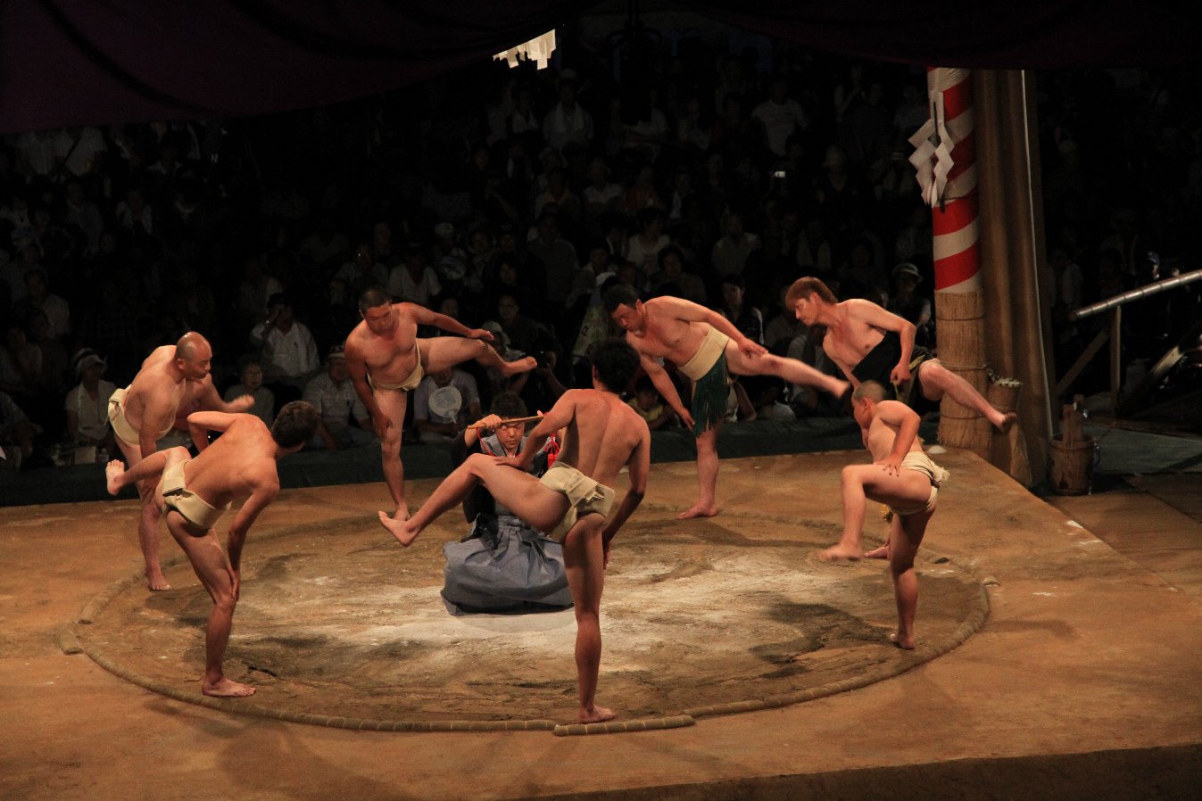 行司を囲んで並んでいる力士たちが左足をあげている写真