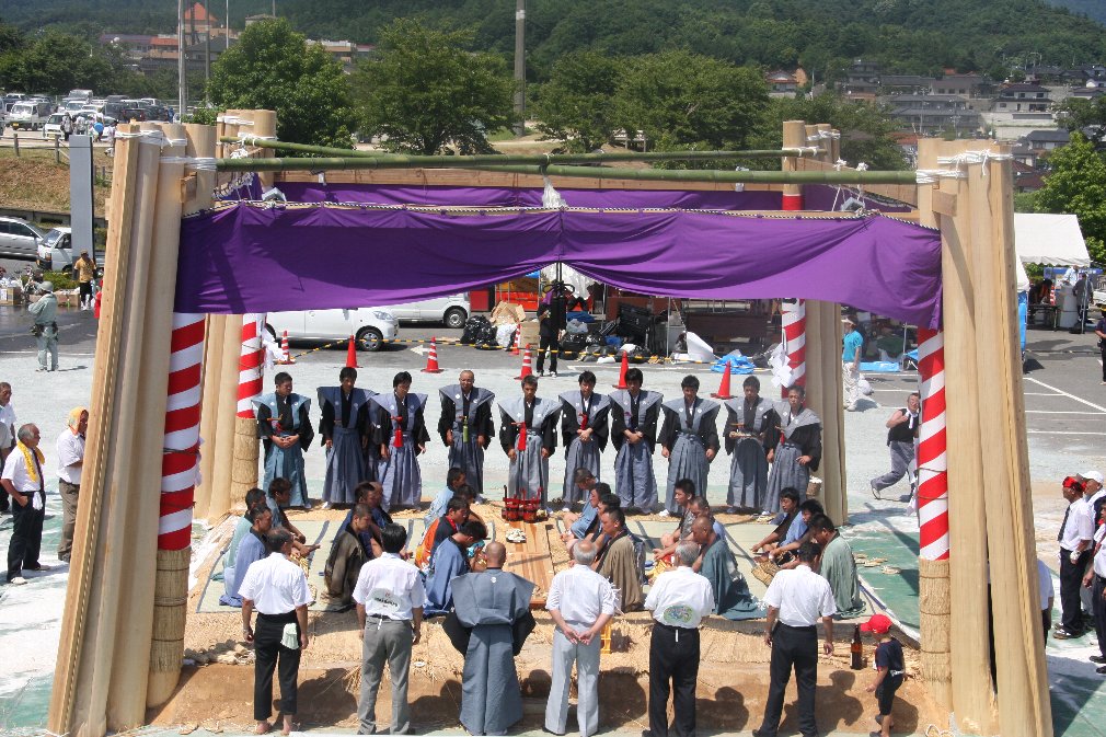 裃を着た人やスーツの人たちが土俵を囲んでいる写真