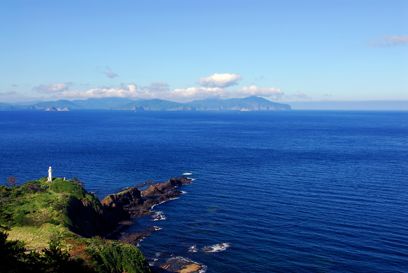 島を遠景に青く澄んだ海が広がる写真