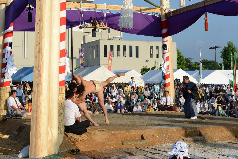 力士が大きく足をあげて相手力士を投げている写真