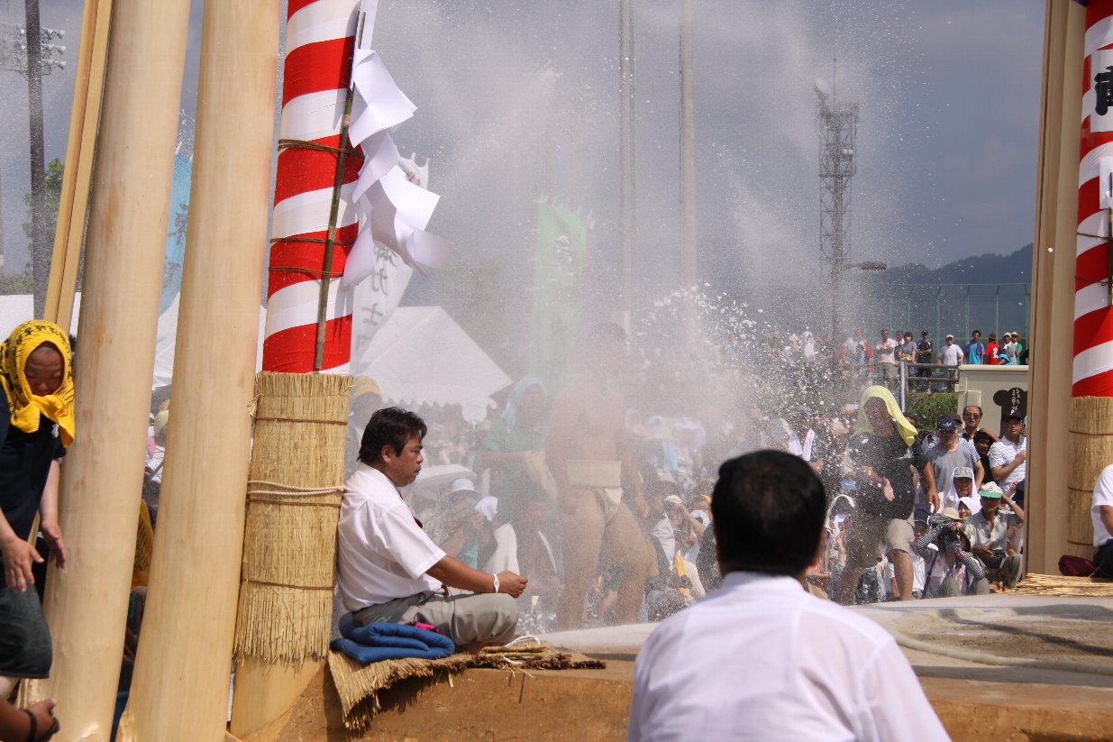 土俵の屋根を支えている支柱にもたれて座っている男性の写真