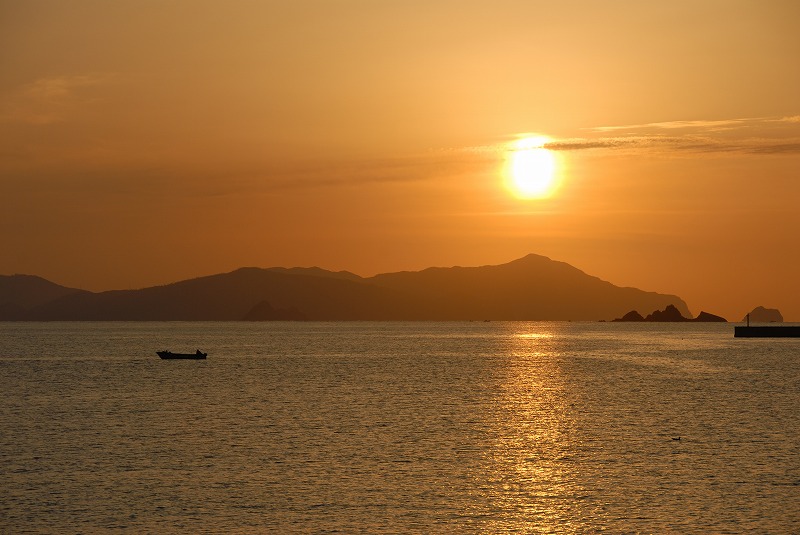 岩山の上に朝日が昇っている写真