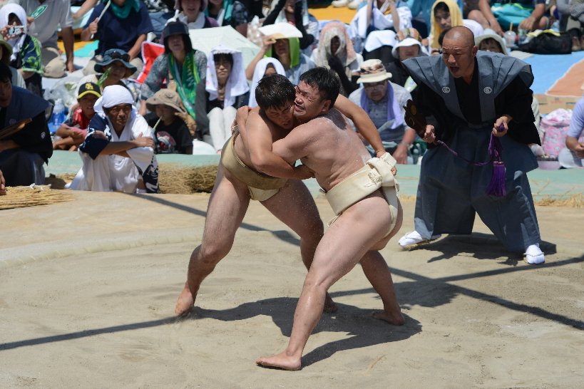 顔をしかめてぶつかり合う二人の力士の写真