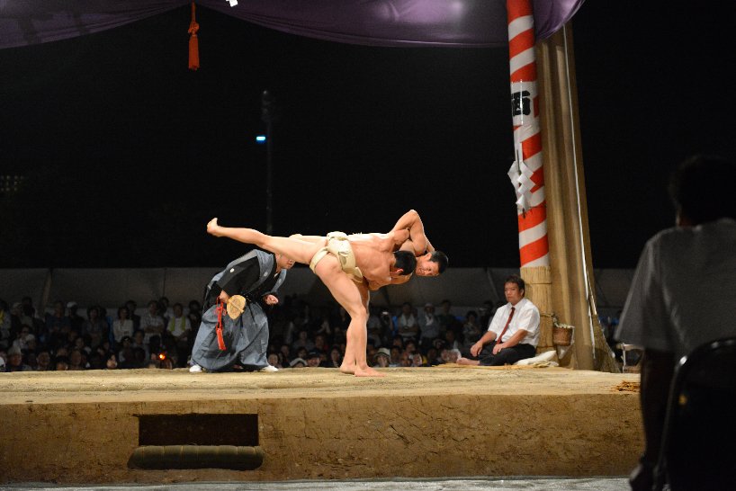 力士が相手力士を土俵外に投げ飛ばそうとしている写真