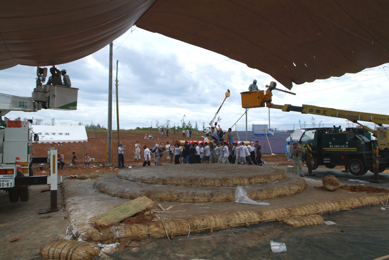 屋外に設置された土俵の周りにトラックが停まっている写真