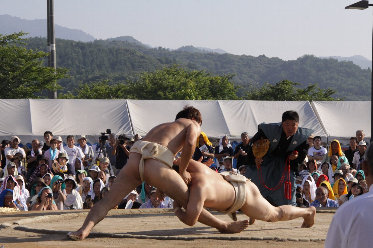 相手力士に向かって倒れそうになる力士の写真