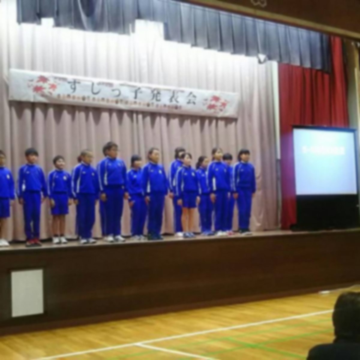 ステージ上で児童たちが横一列になって発表をしている写真