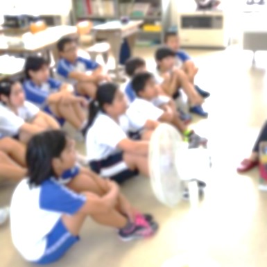 床に座った児童たちが読み聞かせている人を見上げている写真