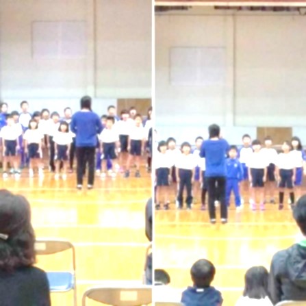 室内で指揮を見ながら合唱する児童たちを観客が見守っている写真