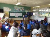 教室で児童が前に立ち、黒板に資料を貼り発表している写真