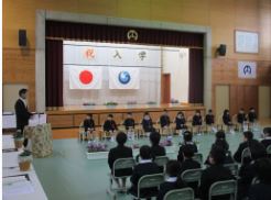 体育館で入学式で新入生と在校生が向き合って座っている写真