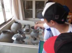 ろくろで作ったような陶器を触っている児童たちの写真